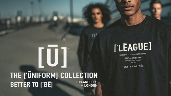 Banner image for clothing site with 3 models standing on an outdoor bridge wearing black t-shirts with the ['LĒAGUE]™ uniform on the front. 